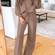 A woman takes a mirror selfie wearing a matching brown lounge set consisting of a long-sleeve V-neck top and wide-leg drawstring pants, 