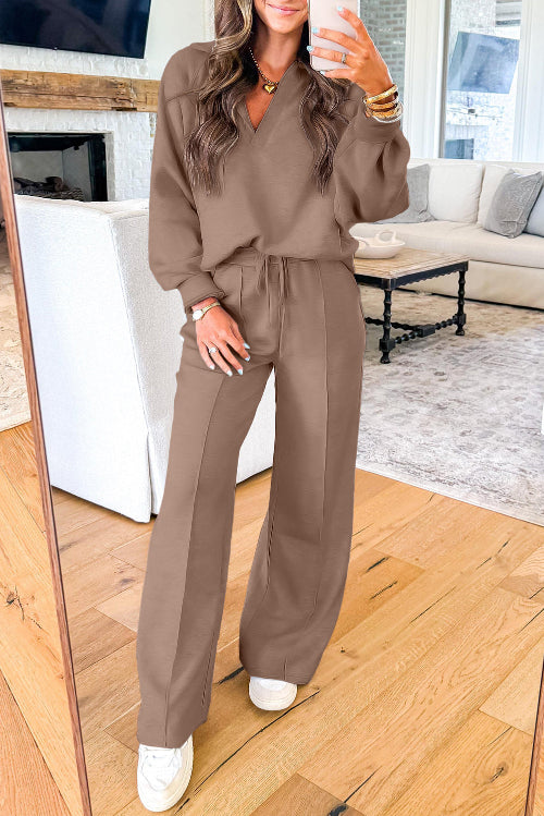 A woman takes a mirror selfie wearing a matching brown lounge set consisting of a long-sleeve V-neck top and wide-leg drawstring pants, 