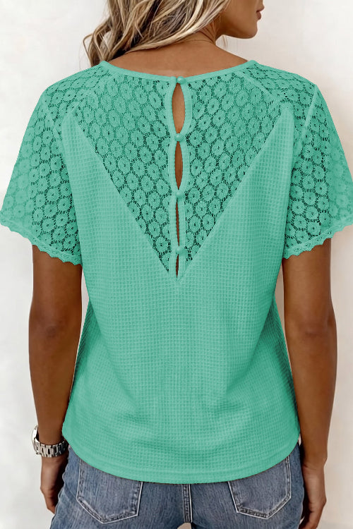 Green lace-trimmed top worn by a person on a white background