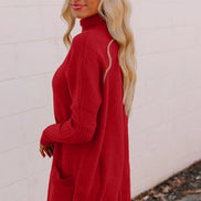 Woman wearing a red sweater dress against a light pink wall.