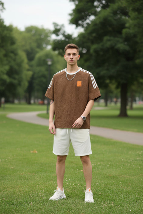 Brown t-shirt with white stripes on sleeves and a small patch on chest, worn by a person.