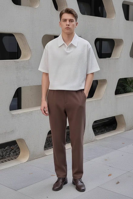 Person wearing a white short-sleeve shirt and brown pants, holding a black bag.