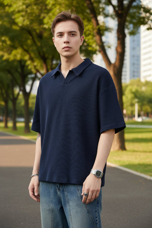 Person wearing a navy blue polo shirt and jeans on a white background