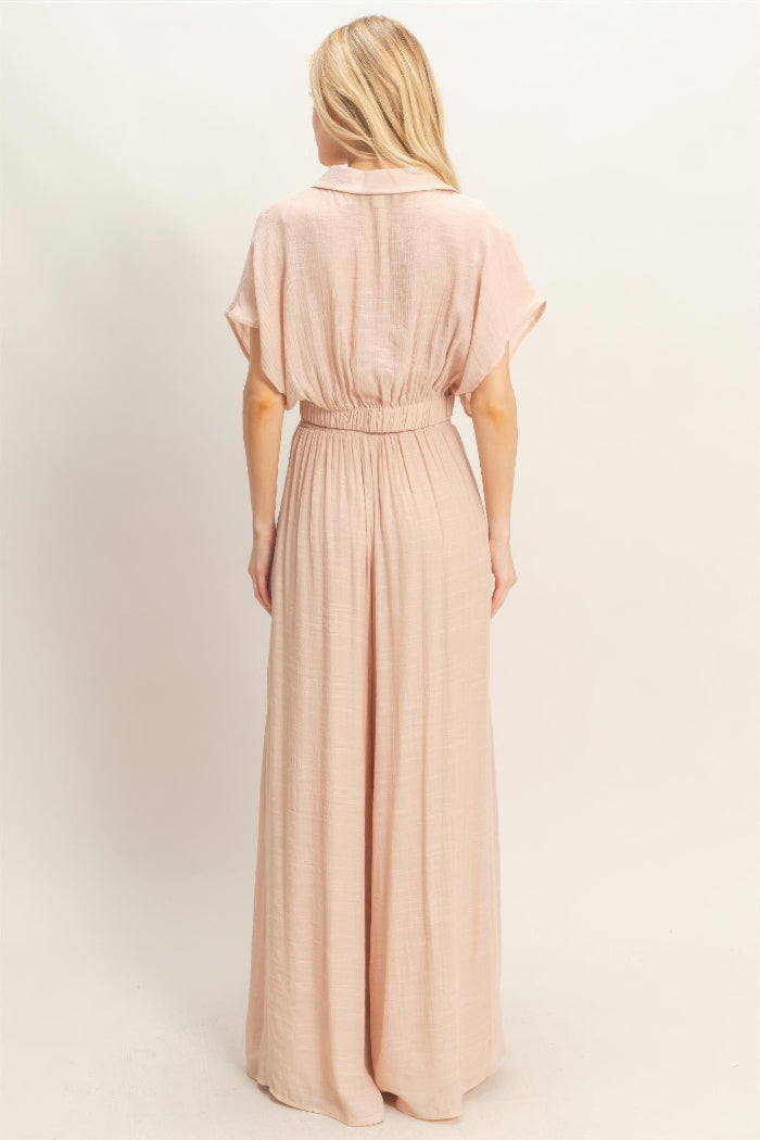 Woman wearing a long, light pink dress against a white background