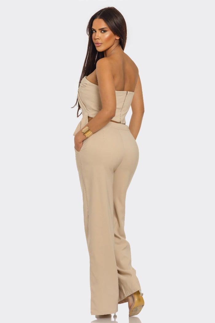 Woman wearing a beige strapless jumpsuit on a white background