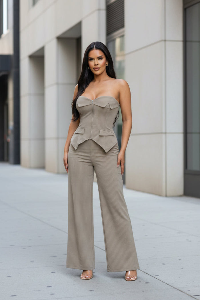 Woman wearing a beige strapless jumpsuit on a white background