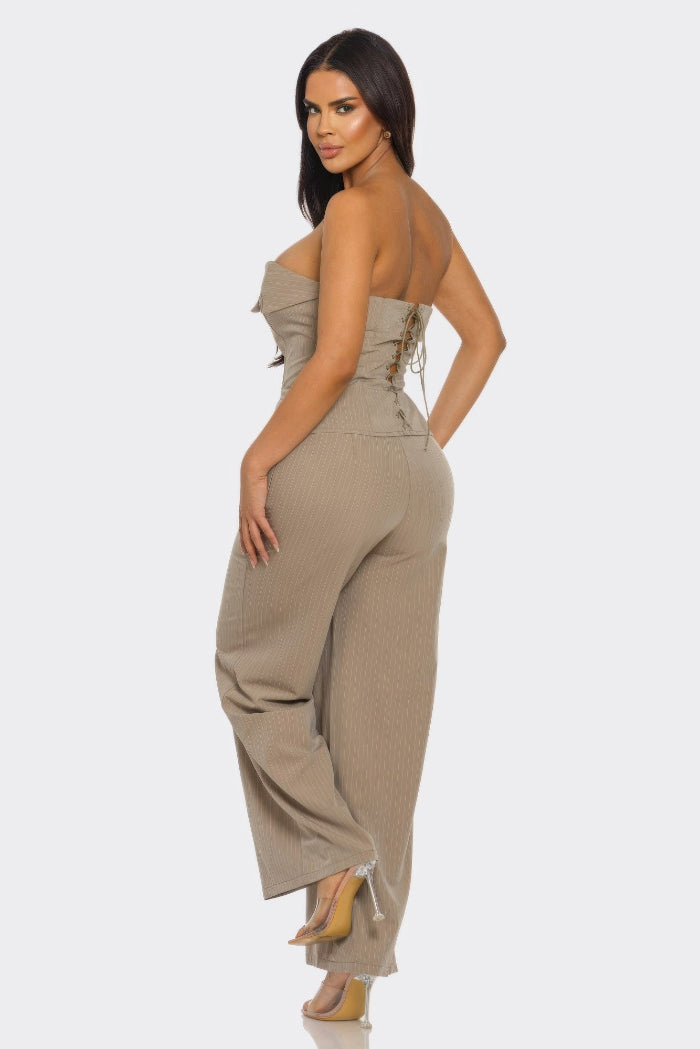 Woman wearing a beige strapless jumpsuit on a white background