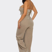 Woman wearing a beige strapless jumpsuit on a white background