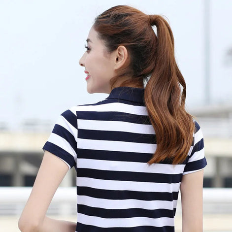 A woman with a brown ponytail is shown from the back wearing a short-sleeve polo shirt with horizontal navy blue and white stripes.
