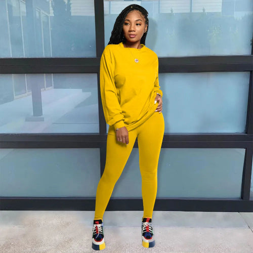 Woman wearing a yellow tracksuit standing in front of a glass wall.