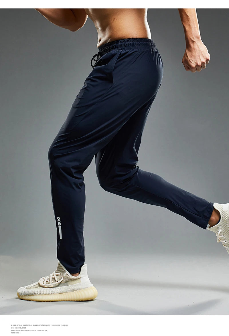 Person wearing navy blue athletic pants and white sneakers on a gray background