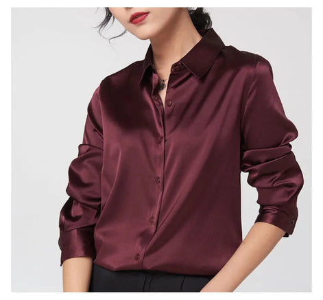 Maroon silk button-front shirt with a pointed collar and rolled sleeves, worn by a model against a light background.