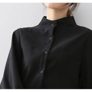 Close-up of a woman wearing a black blouse with a stand collar and button front.