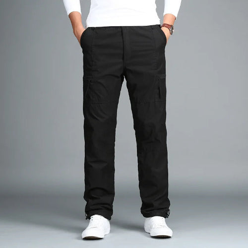Black cargo pants with cargo pockets worn by a man with white sneakers, shown from the front