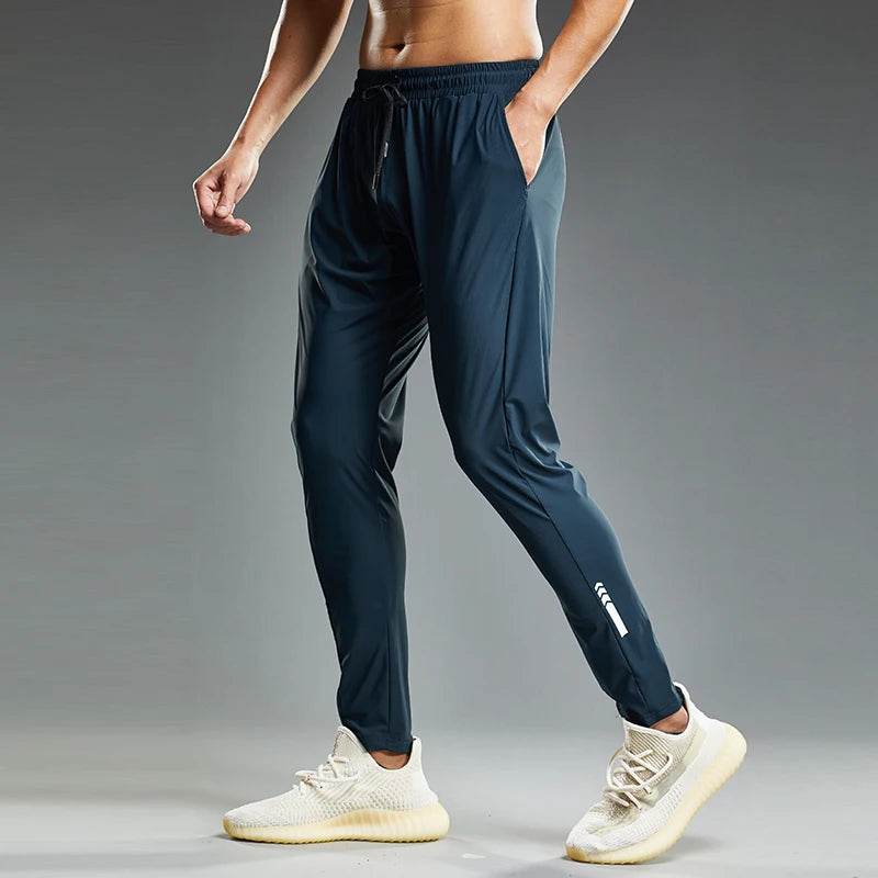 Person wearing navy jogger pants with a gray background