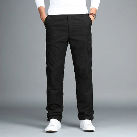 Black cargo pants with cargo pockets worn by a man with white sneakers, shown from the front
