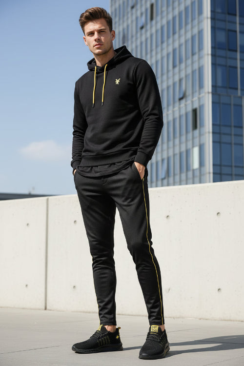 Black athletic shoe with yellow accents on a white background