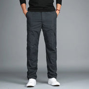 Dark gray cargo pants with cargo pockets worn by a man with white sneakers, shown from the front