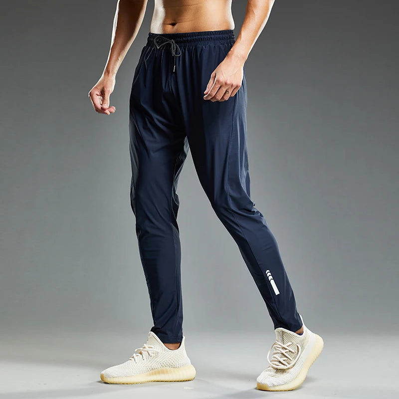 Person wearing navy jogger pants and white sneakers on a gray background