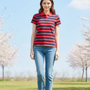 A woman wearing a red and navy blue horizontally striped short-sleeve polo shirt, a black baseball cap, and smiling against an outdoor background.