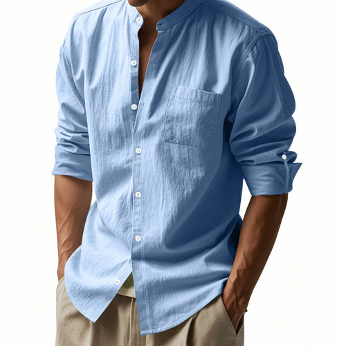 Angled front view of men's light blue linen blend stand collar shirt with a button front, chest pocket, and rolled tab sleeves, worn with khaki trousers