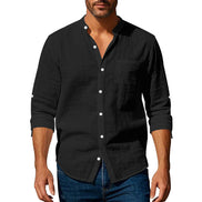 Men's black linen blend stand collar shirt with a button front, chest pocket, and rolled sleeves, worn with dark blue jeans