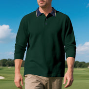 Front view of men's dark green long sleeve polo shirt with a contrasting navy collar and fine collar stripes, modeled on a golf course with sleeves pushed up and khaki trousers