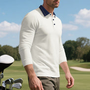 Angled front view of men's white long sleeve polo shirt with a contrasting navy collar and three-button placket, modeled beside golf clubs on a golf course