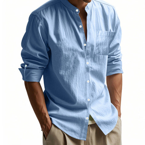 Men's light blue linen blend stand collar shirt with a button front, chest pocket, and rolled tab sleeves, worn with khaki trousers