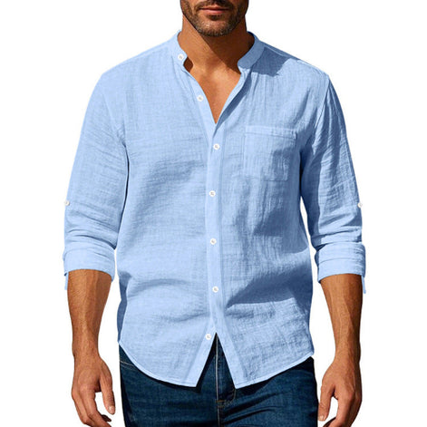 Men's light blue linen blend stand collar shirt with a button front, chest pocket, and rolled sleeves, worn with dark blue jeans