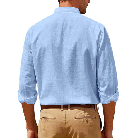 Back view of men's light blue linen blend stand collar shirt with rolled sleeves, tucked into khaki trousers with a brown belt