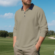 Men's taupe long sleeve polo shirt with a contrasting navy collar and three-button placket, modeled outdoors with sleeves pushed up and taupe trousers