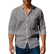 Men's gray linen blend stand collar shirt with a button front, chest pocket, and rolled sleeves, worn with dark blue jeans