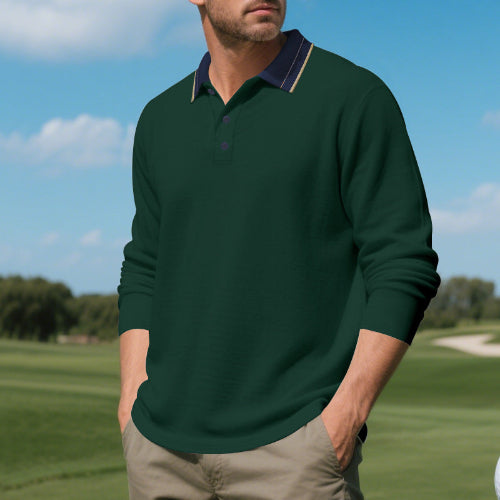 Men's dark green long sleeve polo shirt with a contrasting navy collar and three-button placket, modeled outdoors with sleeves pushed up and taupe trousers