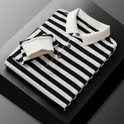 Men's black and white striped long sleeve polo shirt folded to show the white collar, three-button placket, and white cuff