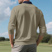 Back view of men's taupe long sleeve polo shirt with a contrasting navy collar and fine collar stripes, modeled outdoors with sleeves pushed up and gray trousers