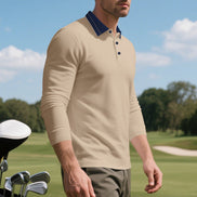 Angled front view of men's khaki long sleeve polo shirt with a contrasting dark collar and three-button placket, modeled beside golf clubs on a golf course