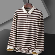 Men's brown and white striped long sleeve polo shirt shown from the front with a white collar, three-button placket, and white cuffs on a wooden hanger
