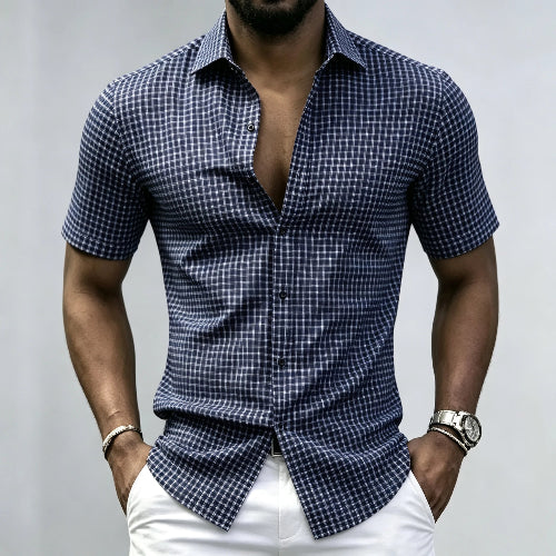 A man wearing a navy blue and white checkered short-sleeve button-down shirt with white pants, 