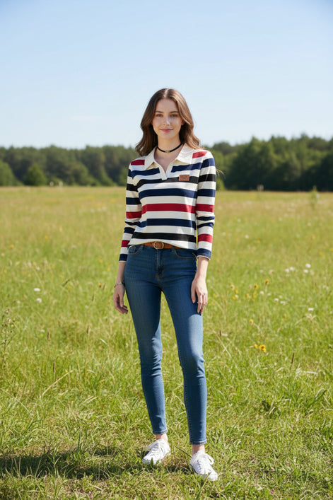 A woman wearing a long-sleeve collared knit top with horizontal stripes in cream, navy blue, black, and red. The top has a small brown patch on the left chest.