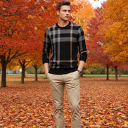 Black and beige plaid sweater worn by a person on a gray background