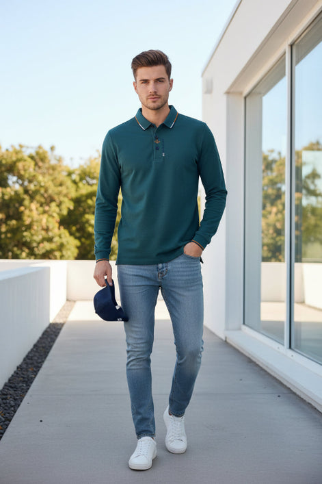 Teal polo shirt with collar and brand logo held by a hand, with blurred background