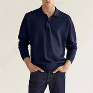 Person wearing a navy blue sweater with a plain background