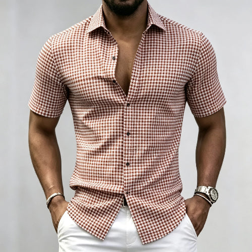 A man wearing a short-sleeve button-up shirt with a brown and white gingham check pattern, 