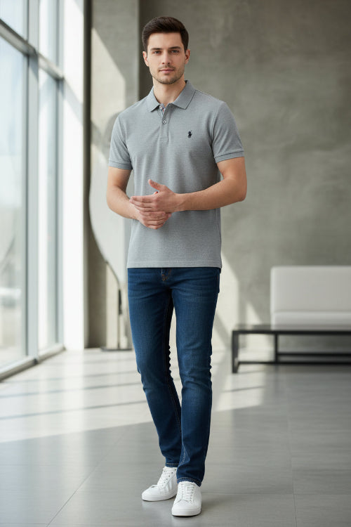 Gray polo shirt with a brand logo held by a hand, with other shirts in the background.