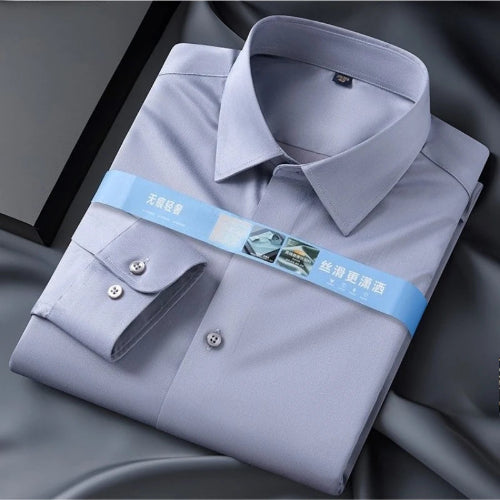 A folded light gray dress shirt with a pointed collar and silver buttons, wrapped in a blue paper band with Chinese text, displayed on a dark gray satin fabric.