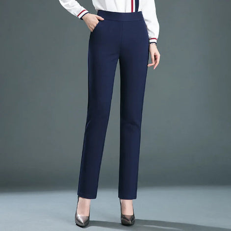 A model wearing navy blue straight-leg trousers, paired with a white long-sleeve top featuring red and blue stripes on the cuffs, 