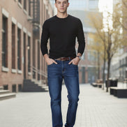 Person wearing blue jeans and brown boots against a dark gray background