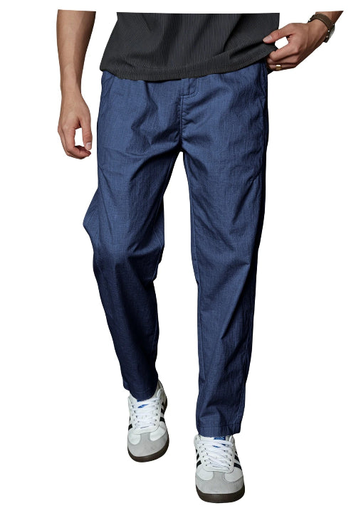 A person wearing dark blue relaxed-fit pants, a dark gray ribbed t-shirt, and white sneakers, shown from the waist down against a plain white background.