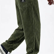 Green corduroy pants worn by a person on a white background